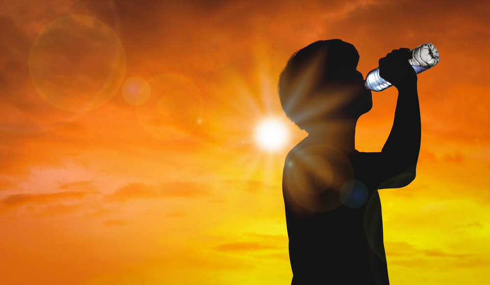 Silhouette man is drinking water bottle on hot weather background with summer season. High temperature and heat wave concept.